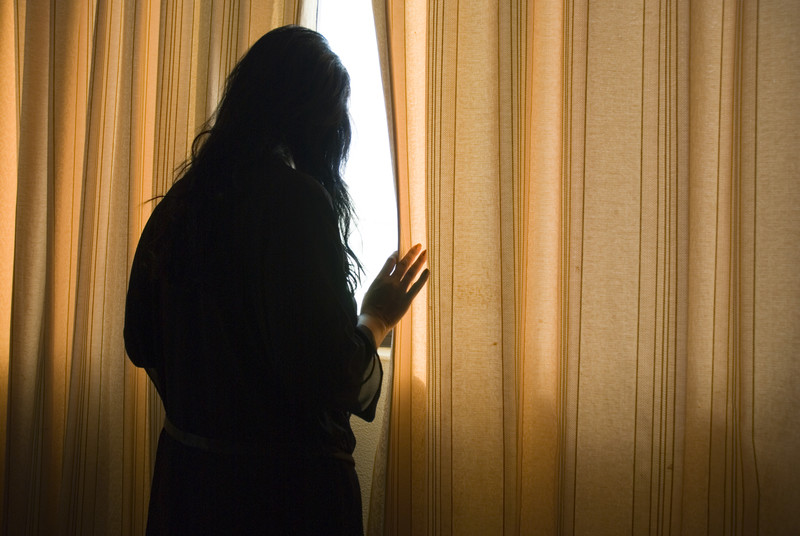 Depression shown in a woman looking out the window as she is lonely